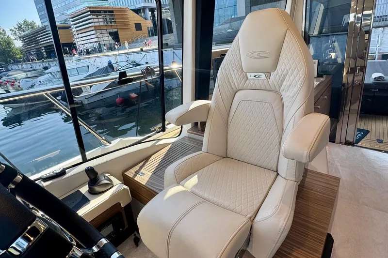 Custom Order Yours Today! Yacht Photos Pics Luxurious interior of 2026 Cobrey 45 FLY yacht with elegant captain's chair and marina view.