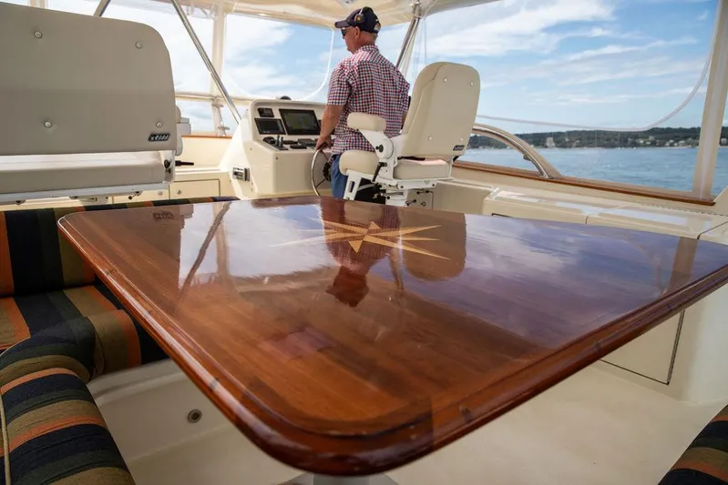 Grace Yacht Photos Pics Flybridge of 2007 Vicem 54 Classic with polished wooden table and captain at helm.