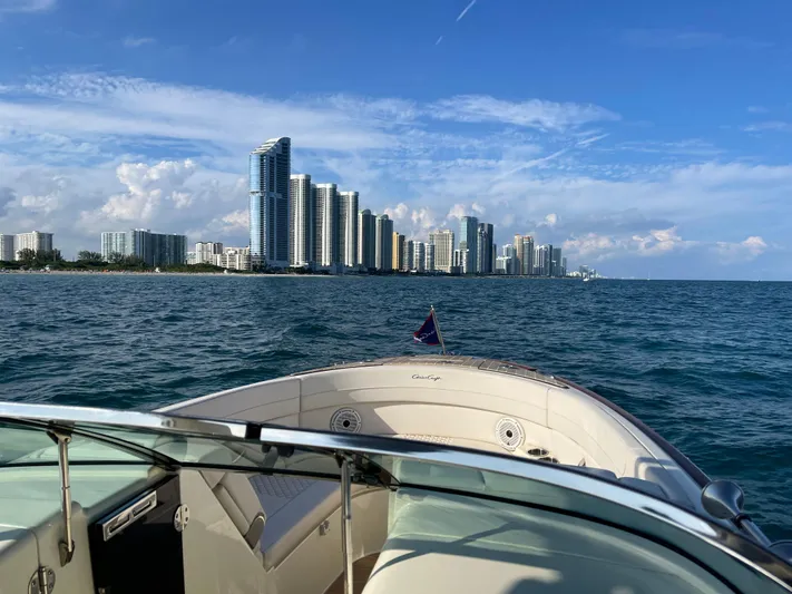  Yacht Photos Pics Chris-Craft 28 Launch GT 2021 boat cruising near a city skyline on a sunny day.