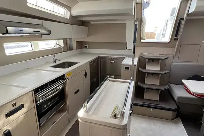 Les Quatre Vents Yacht Photos Pics Modern kitchen interior of 2023 Jeanneau 55 yacht, featuring sleek cabinetry and appliances.