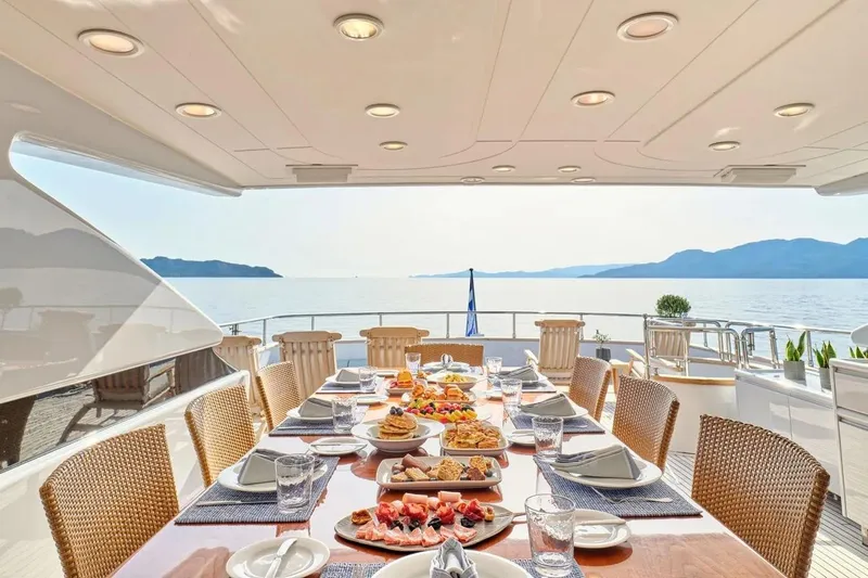 Let It Be Yacht Photos Pics Luxurious dining setup on Tecnomarine 118 yacht, 1998, with ocean view and elegant tableware.