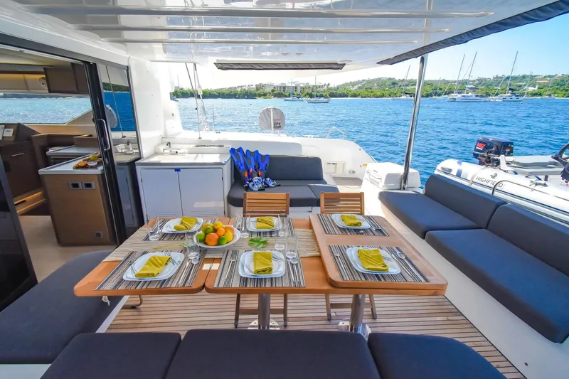  Yacht Photos Pics Luxurious 2021 Lagoon 50 yacht deck with dining setup, overlooking serene blue waters.