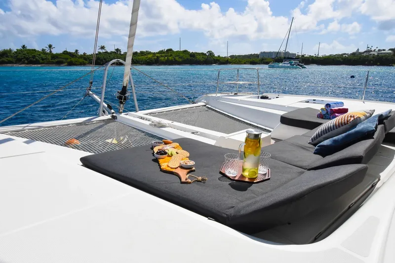  Yacht Photos Pics Luxurious Lagoon 50 catamaran deck with snacks and drinks, anchored in serene blue waters.