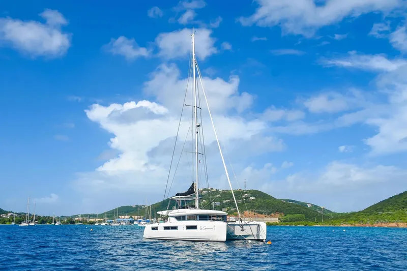  Yacht Photos Pics 2021 Lagoon 50 catamaran sailing in a scenic bay under a clear blue sky.