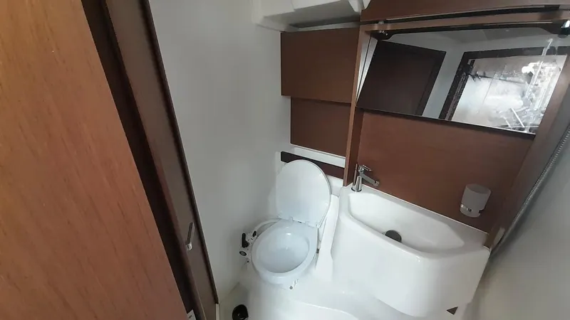 1725 Yacht Photos Pics Modern bathroom in 2022 Beneteau Oceanis 51.1 yacht with toilet, sink, and mirror.
