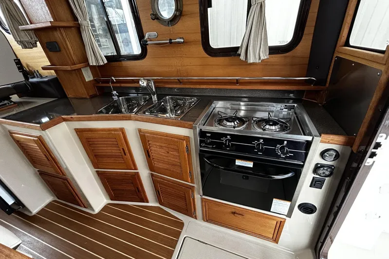 Sequel Yacht Photos Pics 2015 Ranger Tugs R-31 CB galley with stove, sink, and wooden cabinetry.