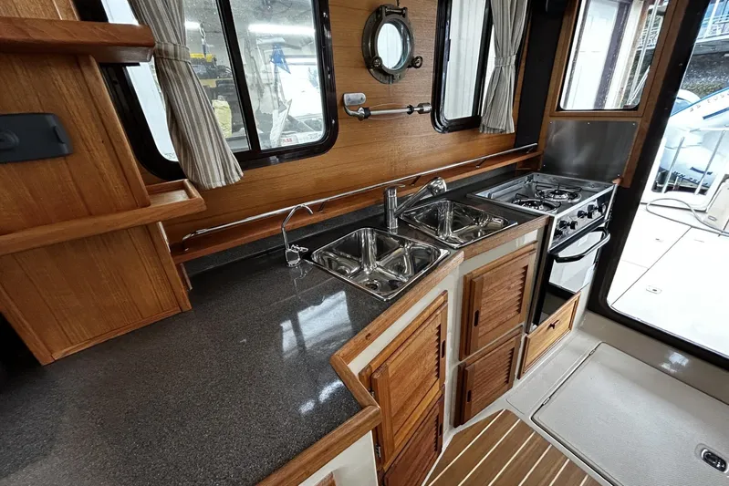 Sequel Yacht Photos Pics 2015 Ranger Tugs R-31 CB interior kitchen with wood cabinetry and stainless steel sink.