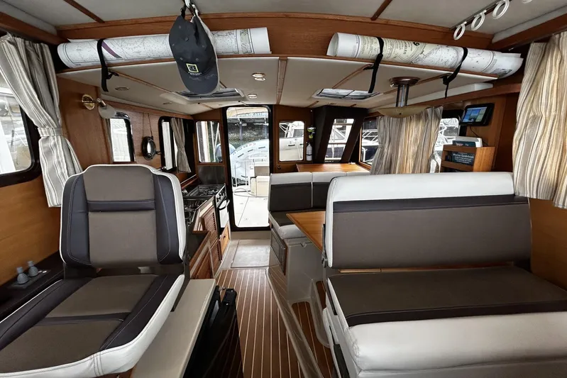 Sequel Yacht Photos Pics Interior of 2015 Ranger Tugs R-31 CB with seating, wood accents, and nautical charts.