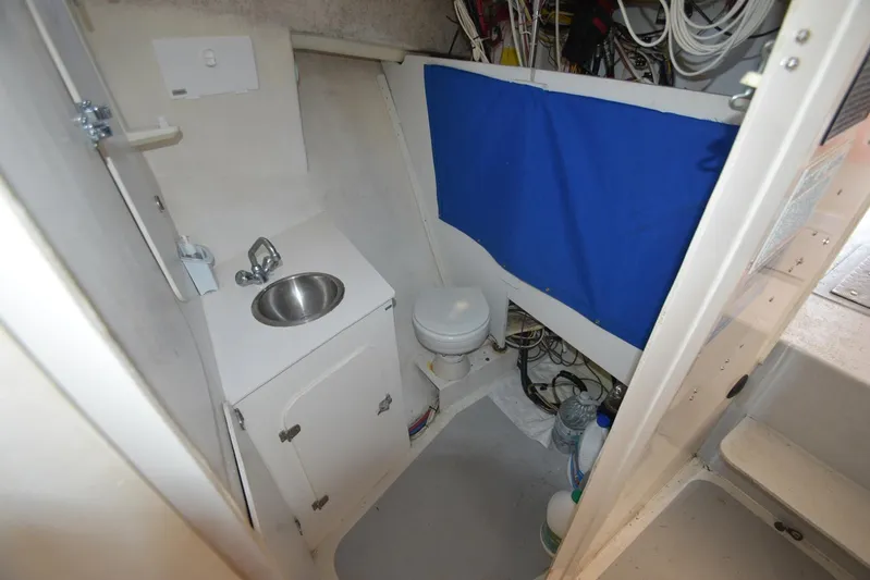 Ocean Explorer Yacht Photos Pics Compact boat bathroom with sink, toilet, and blue curtain in a 2006 Custom 45 Doucette.