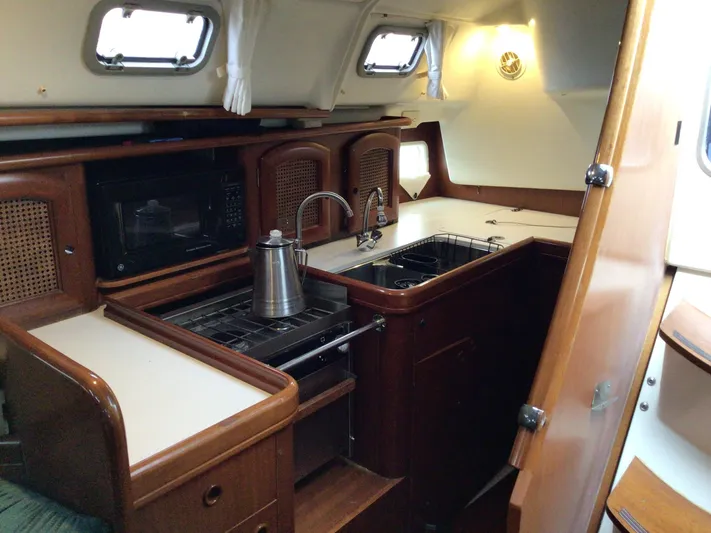 Sao Miguel Yacht Photos Pics Interior of 2000 Beneteau Oceanis 40 yacht kitchen with stove, sink, and microwave.