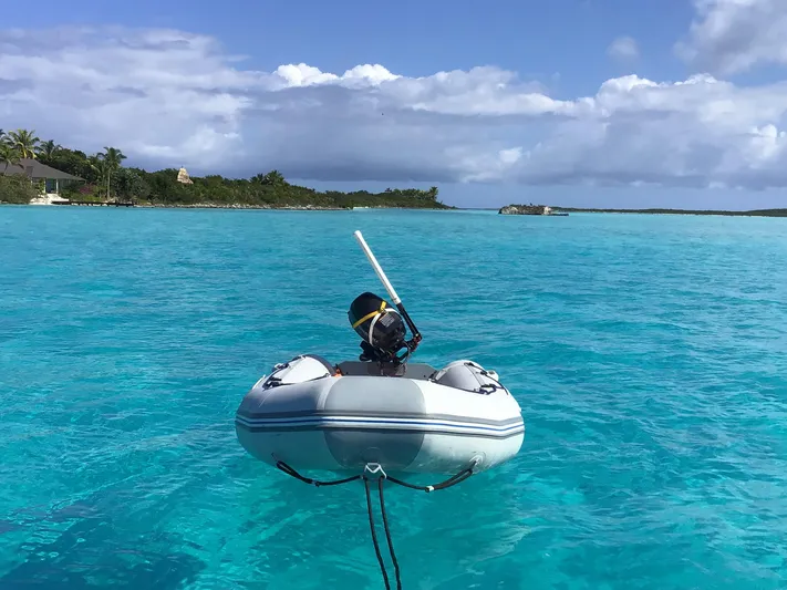 Sao Miguel Yacht Photos Pics Inflatable dinghy floating on turquoise water near lush island, clear skies above.