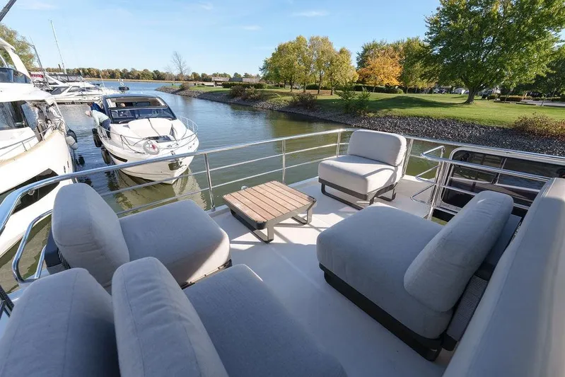 Skyfall Yacht Photos Pics Luxurious 2022 Absolute 52 Navetta yacht with spacious outdoor seating, docked by a serene riverside.