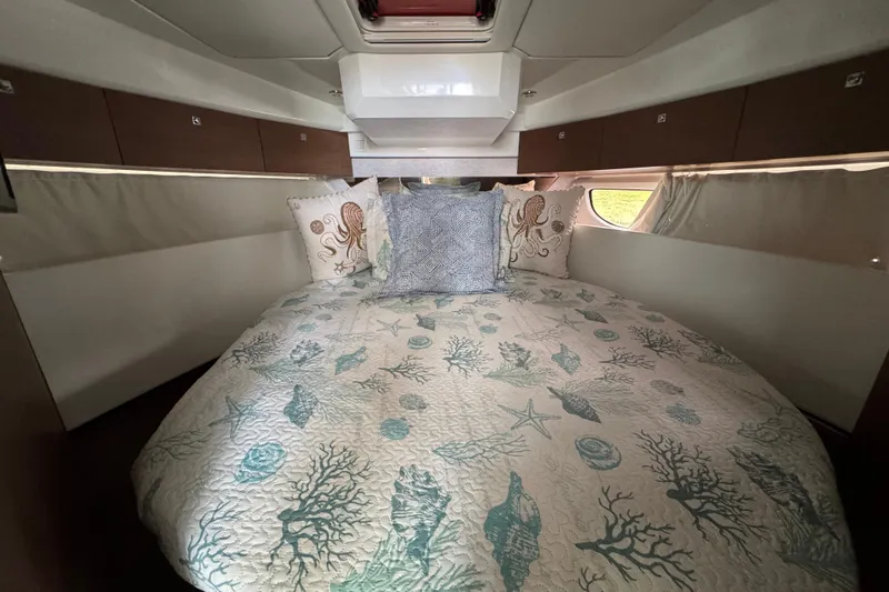  Yacht Photos Pics Luxurious cabin interior of 2022 Jeanneau NC Weekender 1095 with nautical-themed bedding.