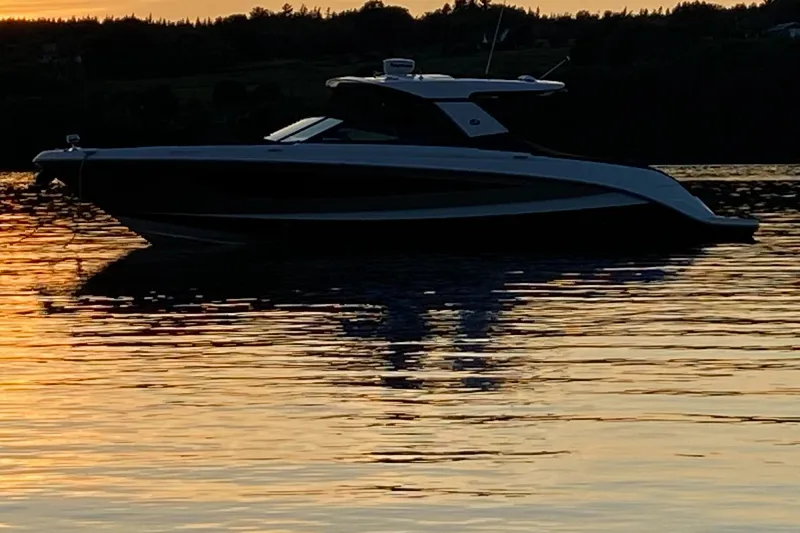  Yacht Photos Pics 2017 Sea Ray SLX 400 boat silhouetted against a sunset on calm water.