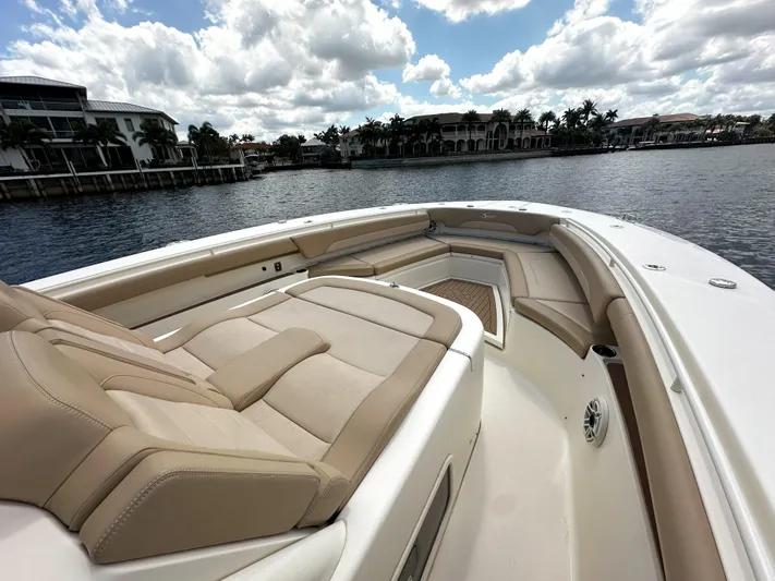  Yacht Photos Pics 2020 Scout 380 LXF boat with luxurious seating, docked by waterfront homes under a cloudy sky.