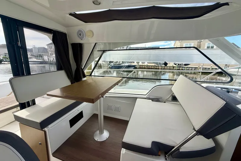  Yacht Photos Pics Interior of 2021 Beneteau Antares 9 with seating and table, overlooking marina.