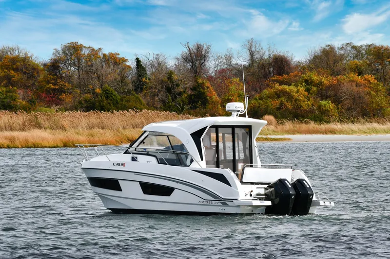  Yacht Photos Pics 2021 Beneteau Antares 9 boat cruising on a scenic lake with autumn foliage.