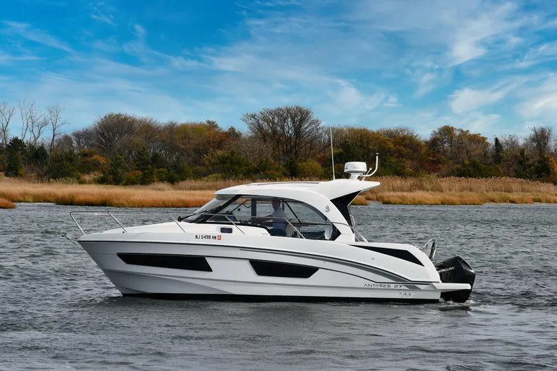  Yacht Photos Pics 2021 Beneteau Antares 9 boat on a calm river with autumn trees in the background.