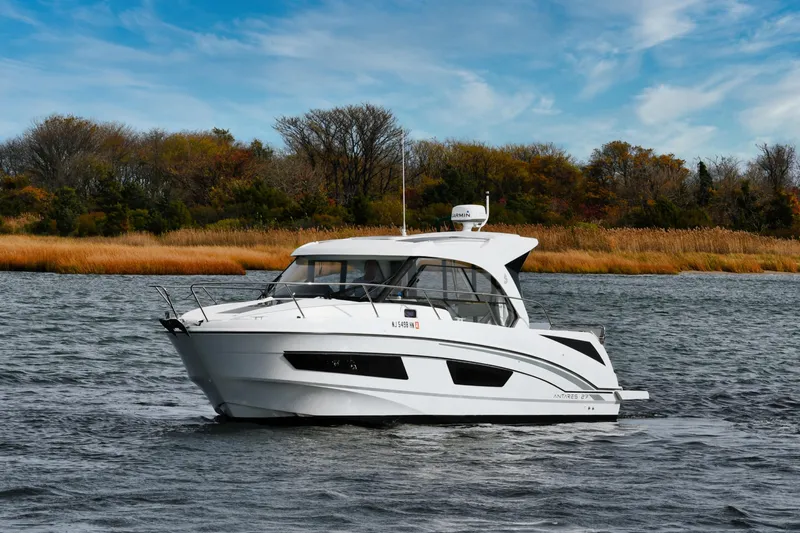  Yacht Photos Pics 2021 Beneteau Antares 9 boat cruising on a scenic river with autumn foliage.