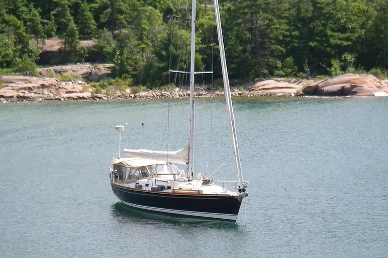 Mistral X Yacht Photos Pics Sailboat Tartan 4300 (2009) anchored in a serene lake with forested shoreline.