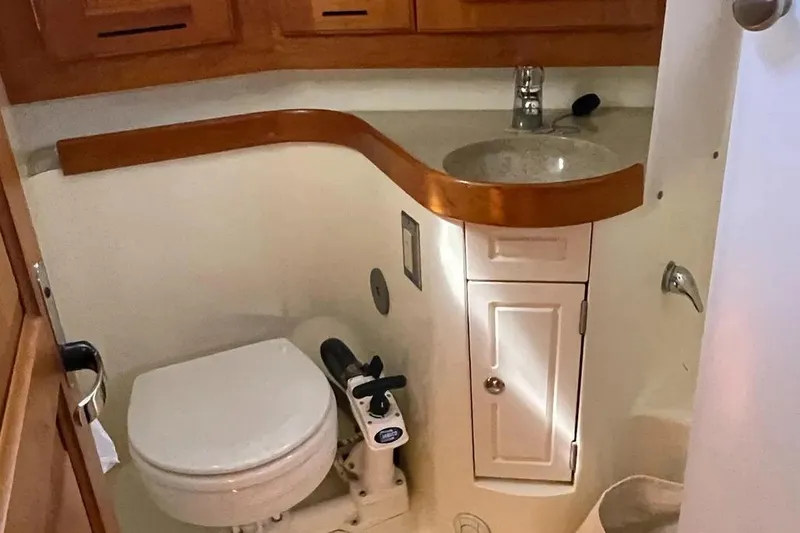 Mistral X Yacht Photos Pics Compact bathroom in 2009 Tartan 4300 yacht with toilet, sink, and wooden cabinetry.