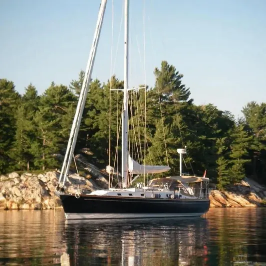 Mistral X Yacht Photos Pics Sailboat Tartan 4300 (2009) anchored near forested shoreline.