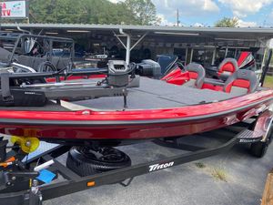 2025 Triton 21XP Patriot boat in showroom, featuring red and gray seating, on a trailer.