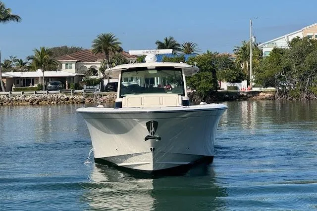  Yacht Photos Pics 2024 Grady-White Canyon 456 boat cruising on calm water near waterfront homes.