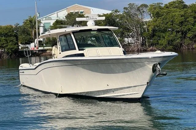  Yacht Photos Pics 2024 Grady-White Canyon 456 boat on calm water, surrounded by trees.