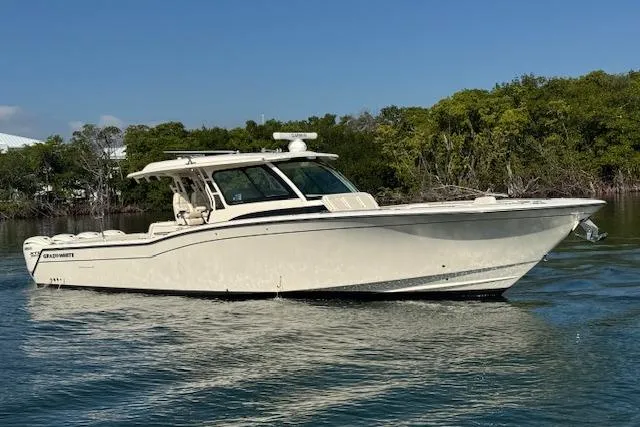  Yacht Photos Pics 2024 Grady-White Canyon 456 boat on calm water, surrounded by greenery.