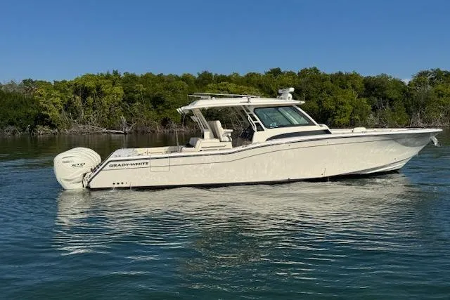  Yacht Photos Pics 2024 Grady-White Canyon 456 boat on calm water, surrounded by lush greenery.
