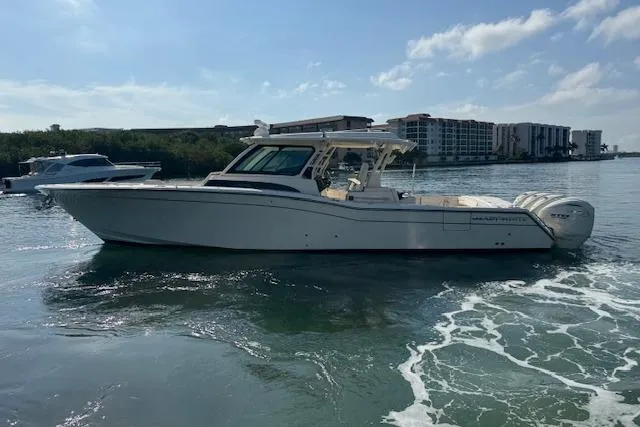  Yacht Photos Pics 2024 Grady-White Canyon 456 boat cruising on a sunny day near waterfront buildings.