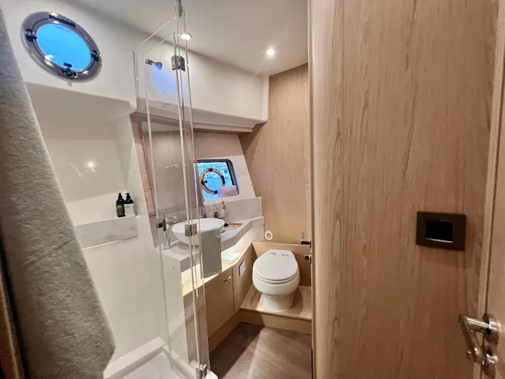  Yacht Photos Pics Modern bathroom on 2025 Beneteau Swift Trawler 54 with shower, toilet, and porthole window.