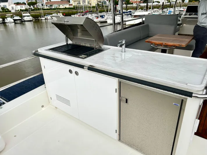  Yacht Photos Pics Outdoor kitchen area on 2025 Beneteau Swift Trawler 54 yacht, featuring a grill and sink.