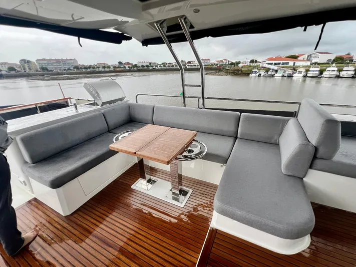  Yacht Photos Pics Beneteau Swift Trawler 54 (2025) deck with gray seating and wooden table by the water.