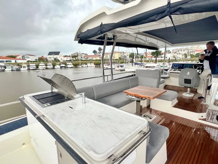  Yacht Photos Pics 2025 Beneteau Swift Trawler 54, spacious deck with seating and grill, docked at marina.