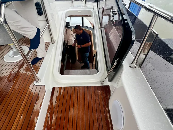  Yacht Photos Pics 2025 Beneteau Swift Trawler 54, teak deck, people entering cabin.