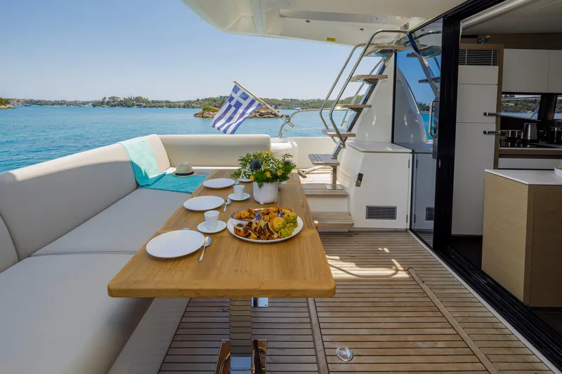 Yacht Photos Pics Luxurious 2022 Prestige 520 yacht deck with dining setup and scenic ocean view.