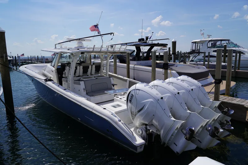  Yacht Photos Pics 2022 Pursuit 428 boat docked with multiple outboard engines, under a clear blue sky.