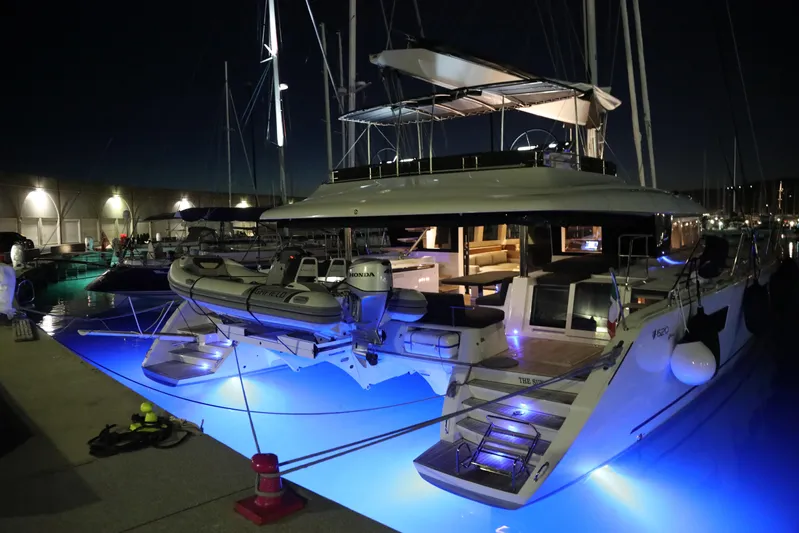  Yacht Photos Pics Luxurious 2020 Lagoon 620 yacht docked at night with blue underwater lights.