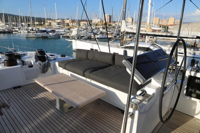  Yacht Photos Pics Luxurious Lagoon 620 yacht deck with seating, table, and steering wheel, docked in a marina.
