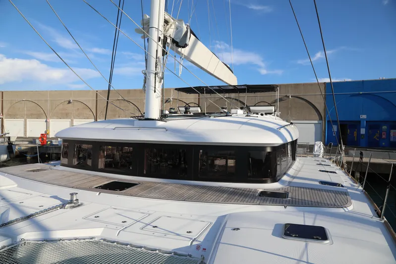  Yacht Photos Pics 2020 Lagoon 620 catamaran docked, showcasing sleek design and spacious deck under clear blue sky.