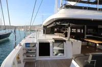Luxurious 2020 Lagoon 620 yacht deck with seating, docked in a marina.