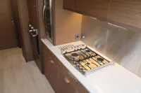 Modern kitchen interior of 2020 Lagoon 620 yacht with sleek wooden cabinetry and gas stove.