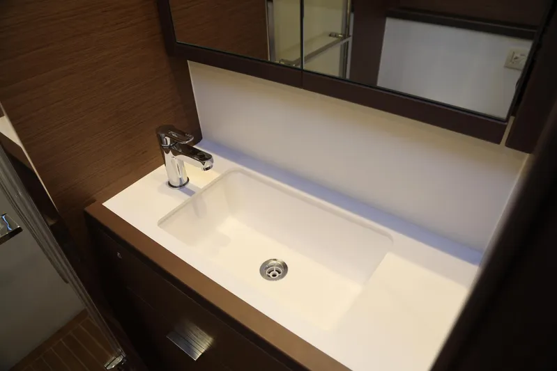  Yacht Photos Pics Modern bathroom sink in 2020 Lagoon 620 yacht, featuring sleek faucet and wooden cabinetry.