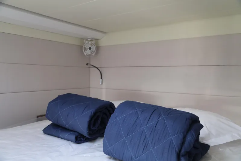  Yacht Photos Pics Cozy cabin interior of 2020 Lagoon 620 yacht with blue bedding and wall-mounted fan.