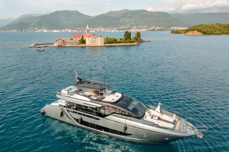 4990 Yacht Photos Pics 2024 Riva 82' Diva yacht cruising near a scenic island with mountains in the background.