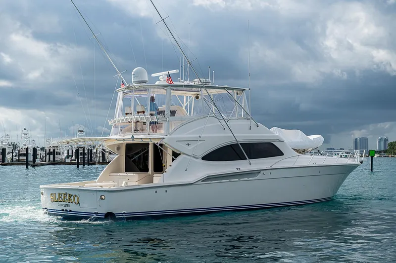  Yacht Photos Pics 2006 Bertram 630 Convertible yacht cruising in a marina under cloudy skies.