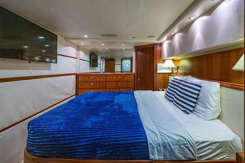  Yacht Photos Pics Luxurious bedroom interior of 2006 Bertram 630 Convertible yacht with blue bedding and wood accents.
