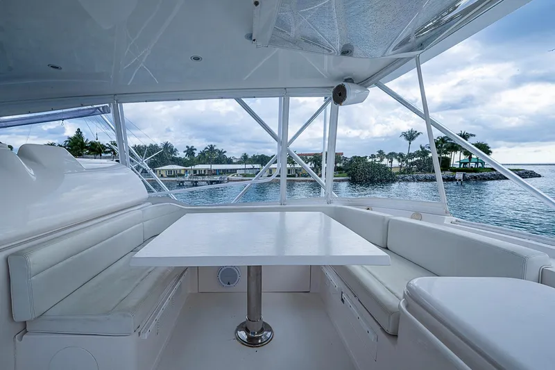  Yacht Photos Pics 2006 Bertram 630 Convertible yacht interior with white seating and table, overlooking serene waters.